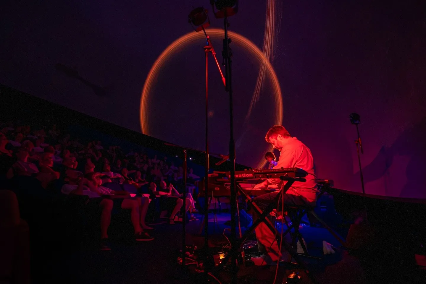 Greg Foat at the keyboards, under a ring of light